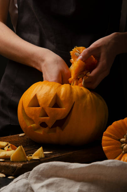 istock Hands cutting, carving pumpkin into jack-o-lanterns for halloween 1188229520