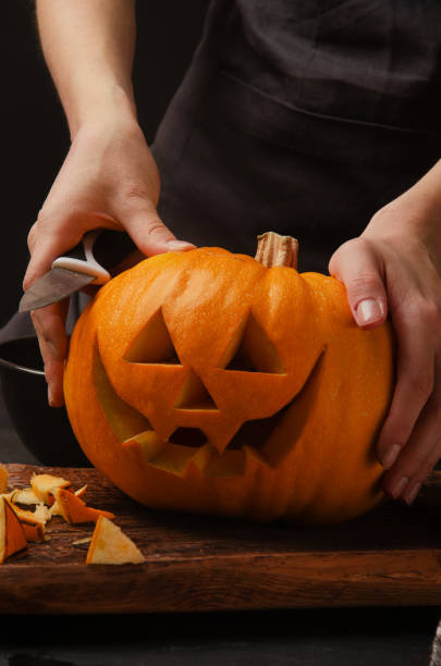 istock Hands cutting, carving pumpkin into jack-o-lanterns for halloween 1188229530