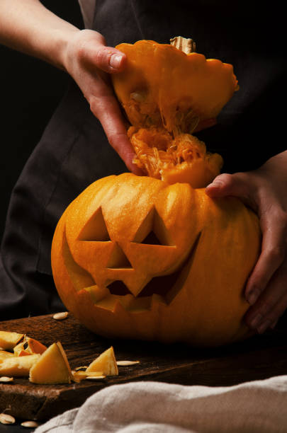 istock Hands cutting, carving pumpkin into jack-o-lanterns for halloween close up 1188229536