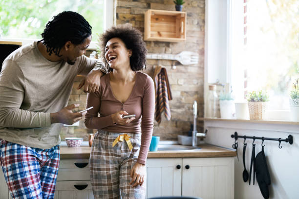 istock Cheerful black couple talking while using cell phones in the morning. 1188233490