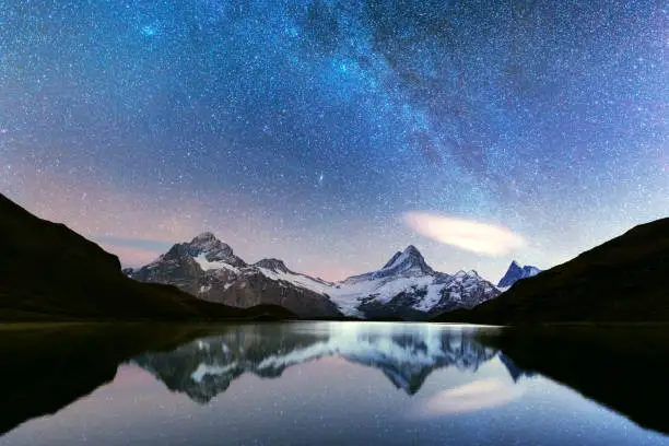 Incredible night view of Bachalpsee lake in Swiss Alps mountains. Snowy peaks of Wetterhorn, Mittelhorn and Rosenhorn on background. Grindelwald valley, Switzerland. Landscape astrophotography