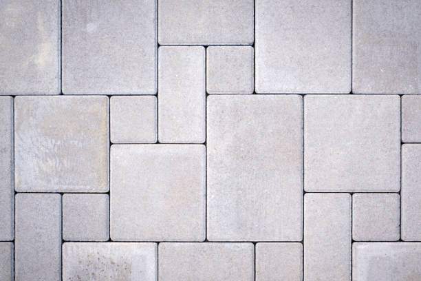 Laying gray concrete paving stones on house courtyard