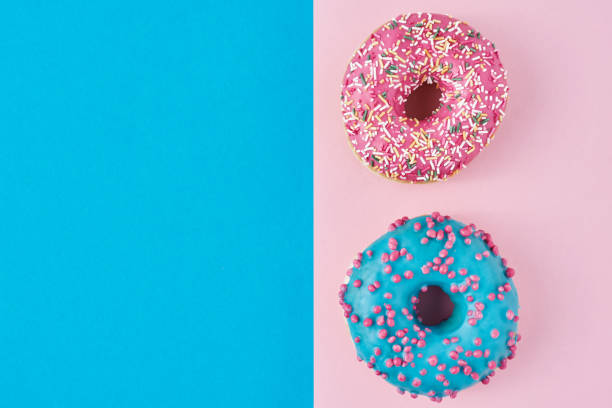 istock Two donuts glazed with sprinkles on a pink and blue background with copy space, top view flat lay. Minimalism concept 1188236460