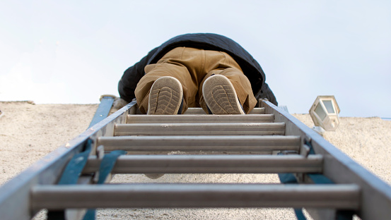 Low angle view of a handyman climbing on a steel ladder. Symmetric pic