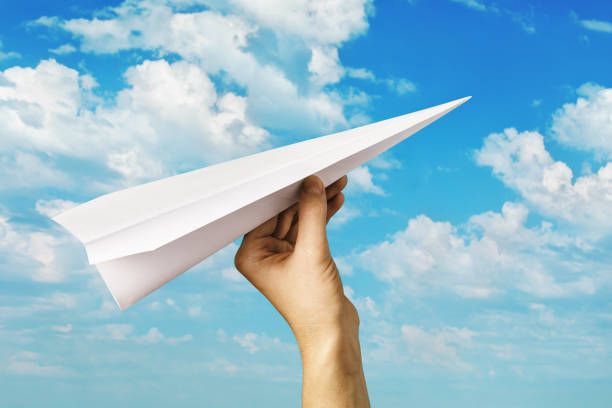 istock A man launches a paper plane into the sky. Hand with a toy airplane. Striving forward 1188239836