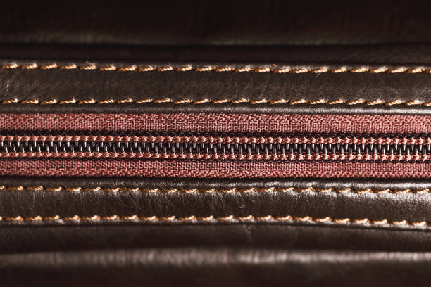Close-up of yellow zipper on leather or leatherette material. Clothes and accessories background. Straight zipper.