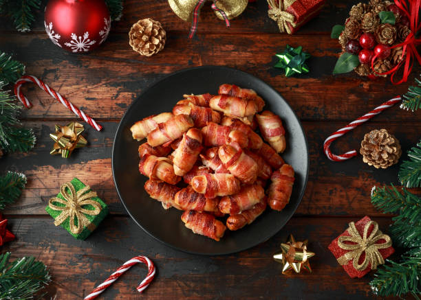 Christmas Pigs in blankets, sausages wrapped in bacon with decoration, gifts, green tree branch on wooden rustic table Christmas Pigs in blankets, sausages wrapped in bacon with decoration, gifts, green tree branch on wooden rustic table. bacon wrapped stock pictures, royalty-free photos & images