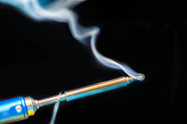 istock soldering iron with smoke on a black background. Electrical 1188246222