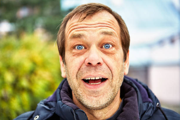 Street photo of a surprised middle-aged man. The surprised face of a man of fifty years old against the background of a European street, close-up. Head of a joyful middle-aged male over 50 outdoors. Unshaven elderly Caucasian with blue eyes. seta stock pictures, royalty-free photos & images