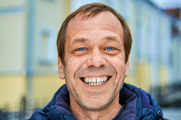 Street photo with a cheerful middle-aged man. Cheerful Caucasian middle-aged man over 50, close-up smiling unshaven face with white teeth and blue eyes. A happy white male of fifty years old on a city street in Europe. seta stock pictures, royalty-free photos & images