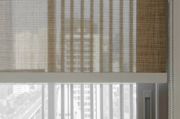 istock Soft focus image. Closeup brown color Roller blinds curtains. sunlight through the windows in the city. Selective focus image. 1188252014