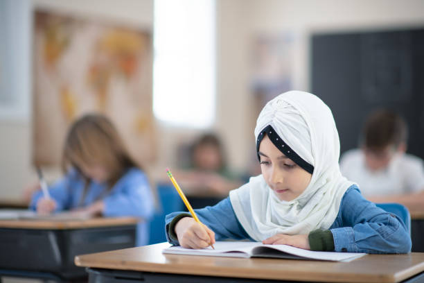 istock Muslim Girl Writing in her Notebook in Class 1188253777