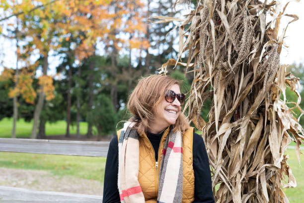 istock stylish middle age woman sitting by cornstalk in Autumn 1188254868