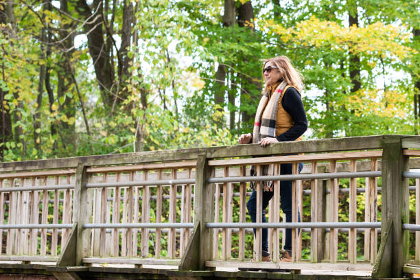 active middle age woman standing outdoors on bridge in autumn