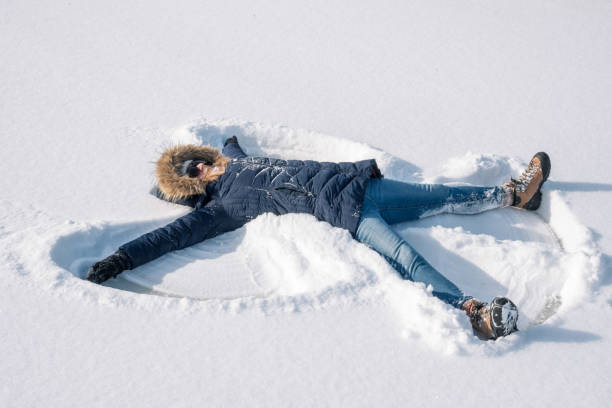 glückliche frau macht schneeengel im winter - butterfly women humor fun stock-fotos und bilder