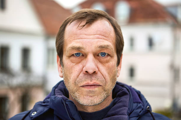 Frowning face of a middle-aged Caucasian man close-up. A serious face of a Caucasian middle-aged man, over 50, close-up, he is an emigrant, unemployed, or has problems. Street portrait of a sad male of fifty years old, in a European city, closeup. expatriate photos stock pictures, royalty-free photos & images