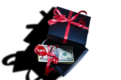 Black gift box with bow with dollars banknotes on white backgroung. top view