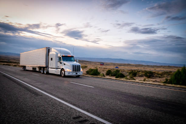 Long Haul Semi Trucks Speeding Down a Four Lane Highway To Delivery Their Loads stock photo