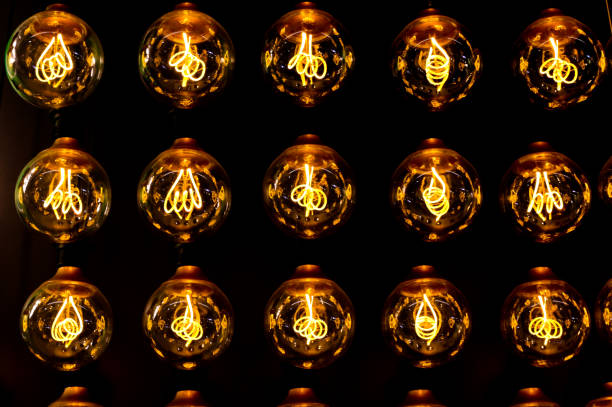 istock Isolated group of yellow gold shining retro classical light bulbs in rows with glowing filaments and black background 1188263008