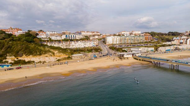 An aerial view of the Boscombe Beach with sandy beach, calm flat water, paddle and pier under a cloudy sky with some blue sky An aerial view of the Boscombe Beach with sandy beach, calm flat water and pier under a cloudy sky with some blue sky boscombe photos stock pictures, royalty-free photos & images