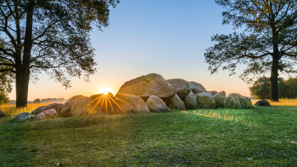 Dutch typical megalith stones in Drenthe Dutch typical megalith stones in Drenthe sunrise just behind the stones with green grass and tree in landscape scene burial mound photos stock pictures, royalty-free photos & images