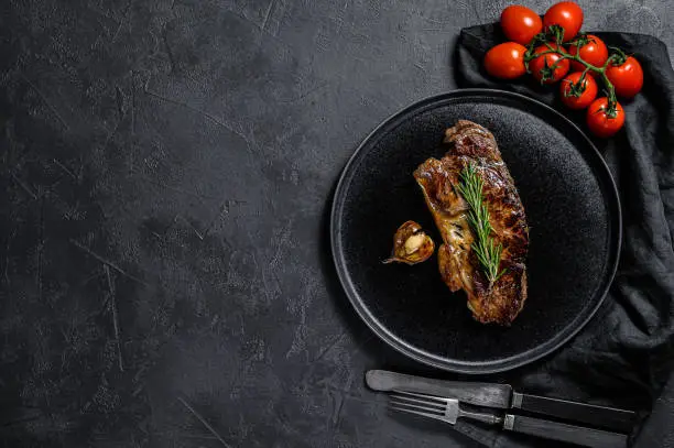 Beef sirloin steak on black background. Space for text. Marble beef