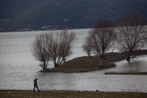 General view of Avlan lake in Elmali near Antalya, Turkey. A photographer is seen on the left side of frame. Shot from a remote position with a full frame DSLR camera during winter time.