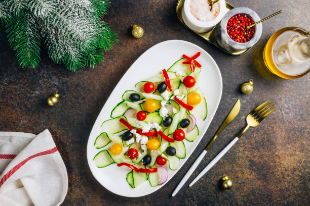 salade grecque de légumes aux tomates, fromage feta, oignons, concombre et olives. forme d'arbre de noel. servi sur une assiette blanche sur la table de fête. vue du haut. flat lay. espace de copie - christmas lunch mediterranean cuisine color image photos et images de collection