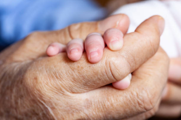 Close Up Photo Of Senior Hands Holding Baby Hands Full frame close up photo of senior men and baby hands. They are holding each others hands. Shot with a full frame DSLR camera and a macro lens. old man baby stock pictures, royalty-free photos & images