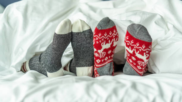 świąteczne skarpetki z rodziny kilka stóp relaks na łóżku o dobry czas snu razem, ciesząc się odpoczynku w domu w sypialni na zimowe wakacje boże narodzenie i obchody nowego roku - cold feet zdjęcia i obrazy z banku zdjęć