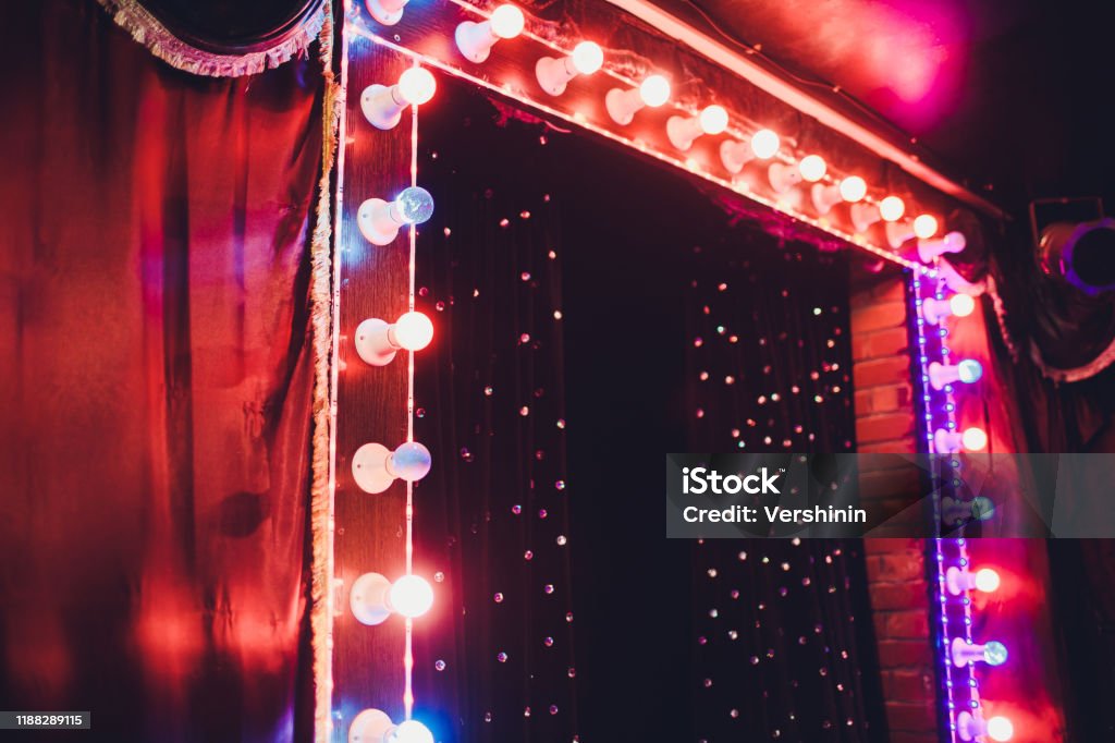 Light Bulbs On Stage Theatrical scene with colored glitter neon bulbs for presentation or concert performance. Night show in festive evening. Light Bulbs On Stage Theatrical scene with colored glitter neon bulbs for presentation or concert performance. Night show in festive evening Cabaret Stock Photo