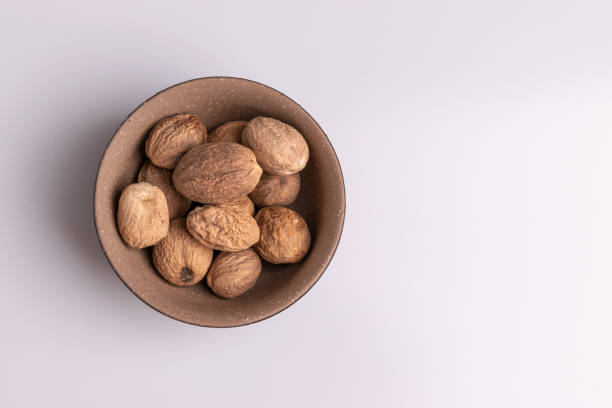 istock Nutmeg spice in a ceramic bowl isolated on white background, soft light, studio shot, copy space 1188295052