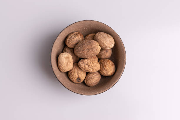 istock Nutmeg spice in a ceramic bowl isolated on white background, soft light, studio shot, copy space 1188295082