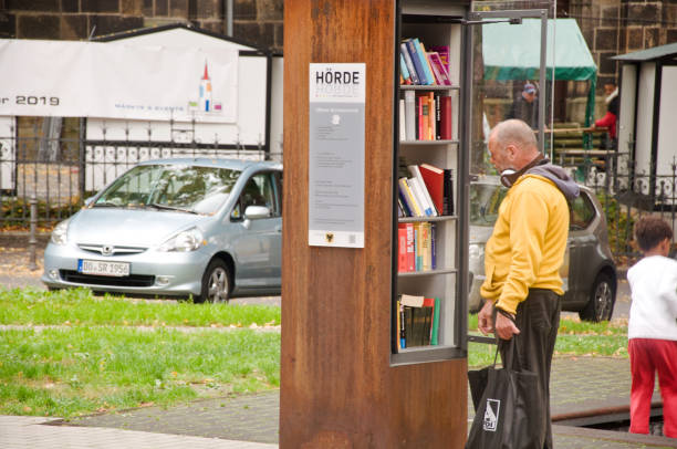transeunte que olha para pedir um livro de uma prateleira de livro livre da comunidade em dortmund hoerde em alemanha - men reading outdoors book - fotografias e filmes do acervo