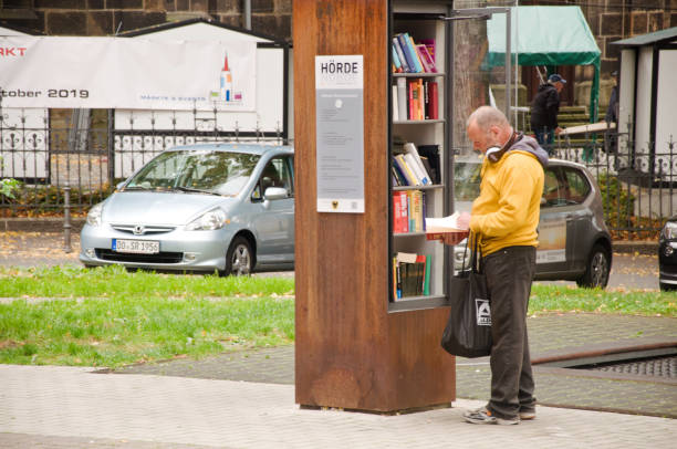 transeunte que olha para pedir um livro de uma prateleira de livro livre da comunidade em dortmund hoerde em alemanha - men reading outdoors book - fotografias e filmes do acervo