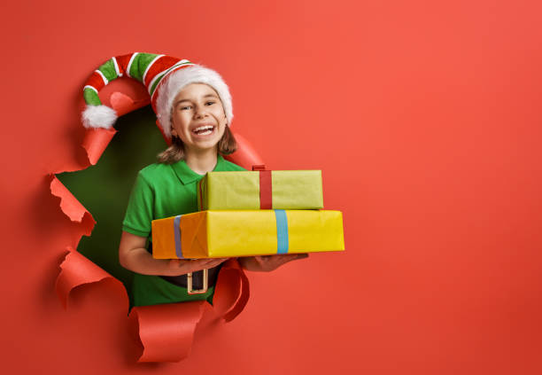 girl in Santa's hat on bright color background Merry Christmas! Little girl in Santa's elf costume on bright color background. Red and green. santa claus elf assistance christmas stock pictures, royalty-free photos & images