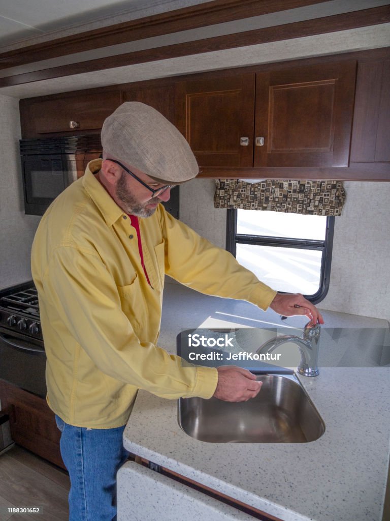 Man washing hands in RV sink Man using a sink in a motorhome Motor Home Stock Photo