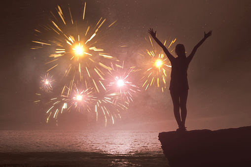 Silhouette of a woman with a happy expression celebrating the new year with fireworks on the sky. Happy New Year 2020