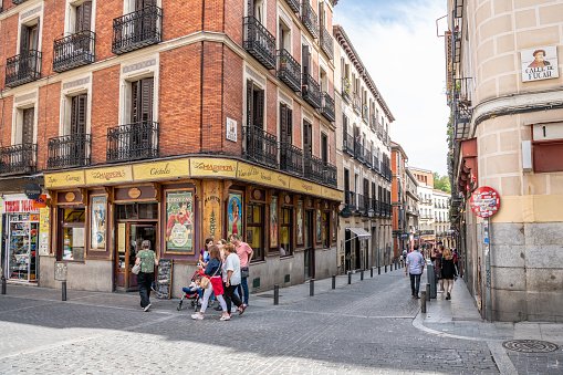 Madrid, Spain / October 12, 2019: People wander the beautiful back streets of the Huertas and Las Letras neighborhood in Central Madrid, surrounded by typical Spanish architecture.