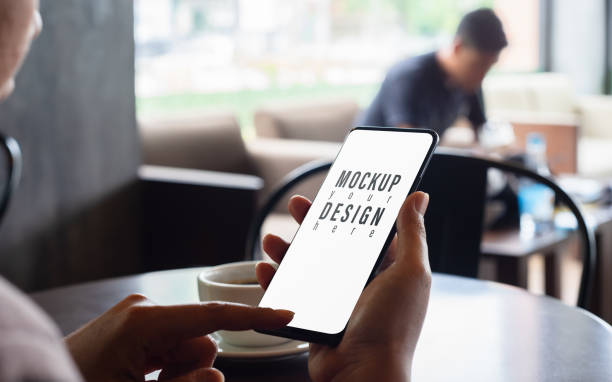 istock Mockup image of hand holding and using mobile smart phone with blank white screen in a coffee shop 1188307690