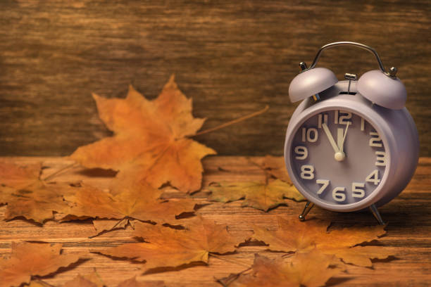 istock clock on old wooden background decorated with autumn leaves 1188310584