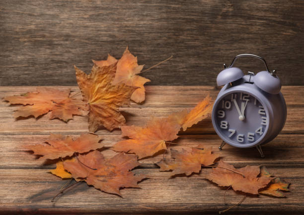 istock clock on old wooden background decorated with autumn leaves 1188310600