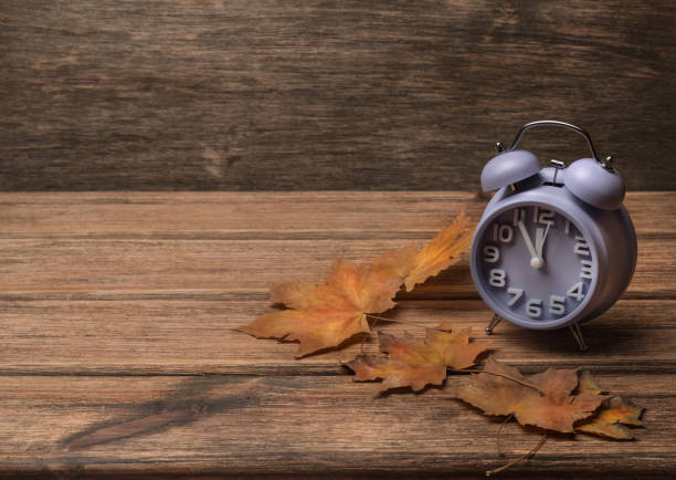 istock clock on old wooden background decorated with autumn leaves 1188310673