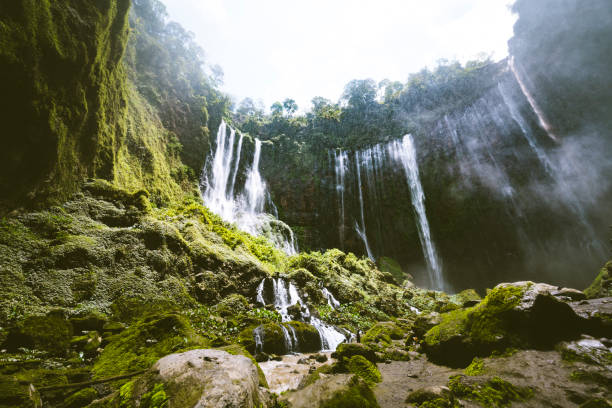 Aerial view deep inside the canyon of the Tumpak Sewu waterfall located in Java, Indonesia. The source of the waterfall comes from Semeru, an active volcano and the highest mountain in Java.