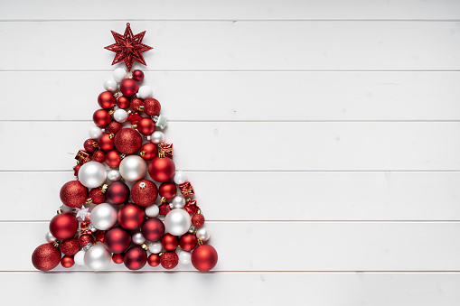 Christmas tree made of bauble decoration on white wooden boards. Minimal New year concept.