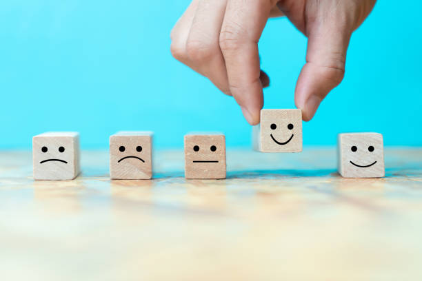 Businessman chooses a happy emoticon icons face on wooden block. stock photo