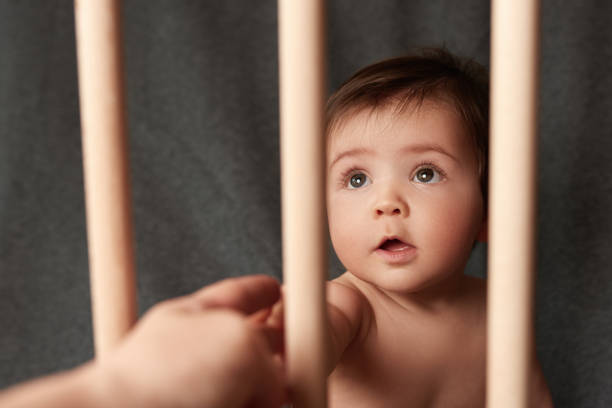 A Chinese baby boy is holding railing at home.