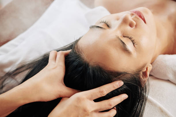 Professional head massage Close-up image of beautician massaging head of female client relaxing on massage bed relaxation lying on back women enjoyment stock pictures, royalty-free photos & images