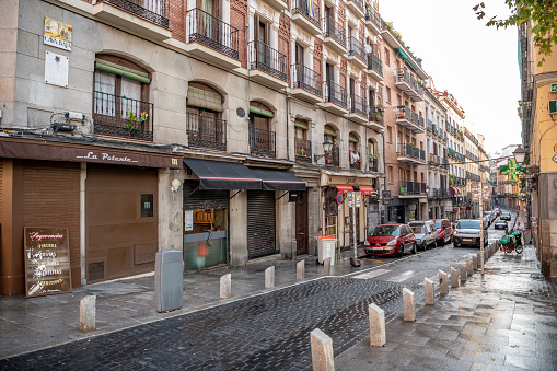 Madrid /Spain - October 13, 2019:  Scenic street scene in the La Latina / La Ribera neighborhood, with stone streets  and parked cars and store fronts visible.