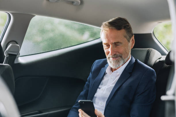 istock Businessman sitting in the car using a smartphone. Man checking cell phone on a backseat. 1188325959